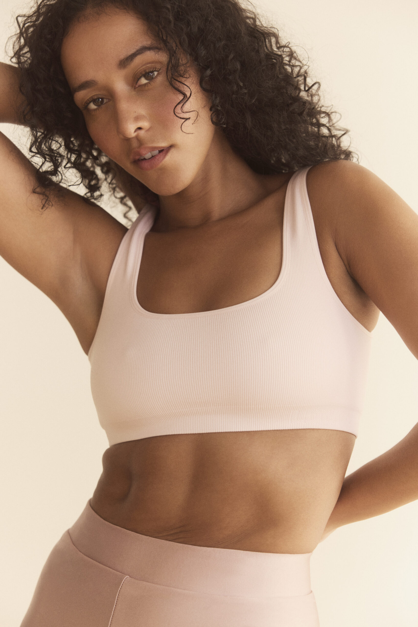Young woman posing in pastel pink sportswear.